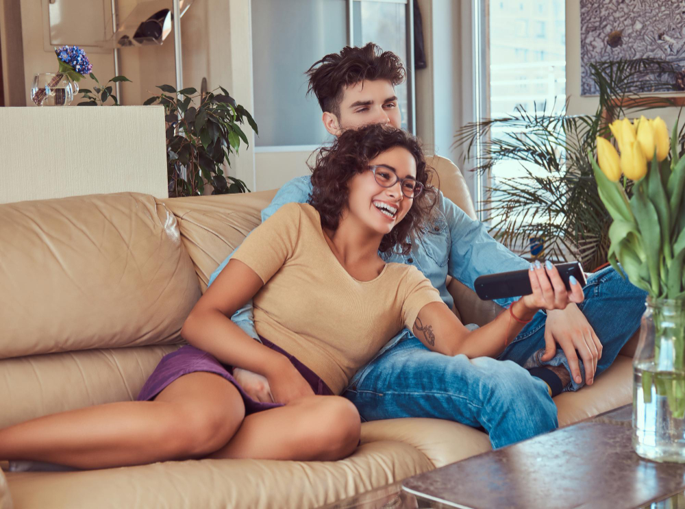 happy young couple cuddling while watching tv their living room