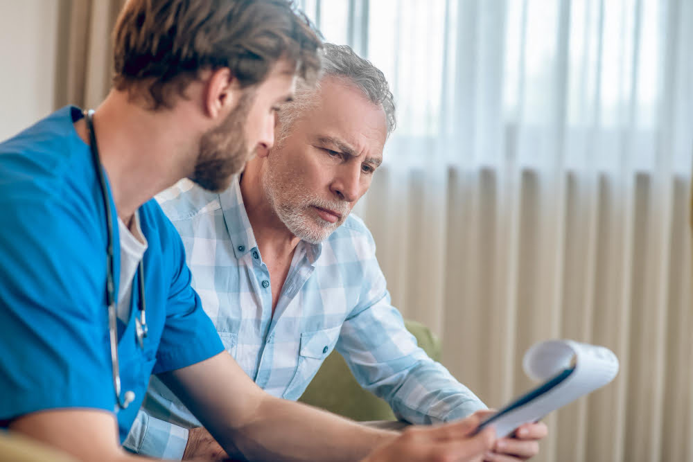 focused serious gray haired man plaid shirt looking clipboard doctor hands